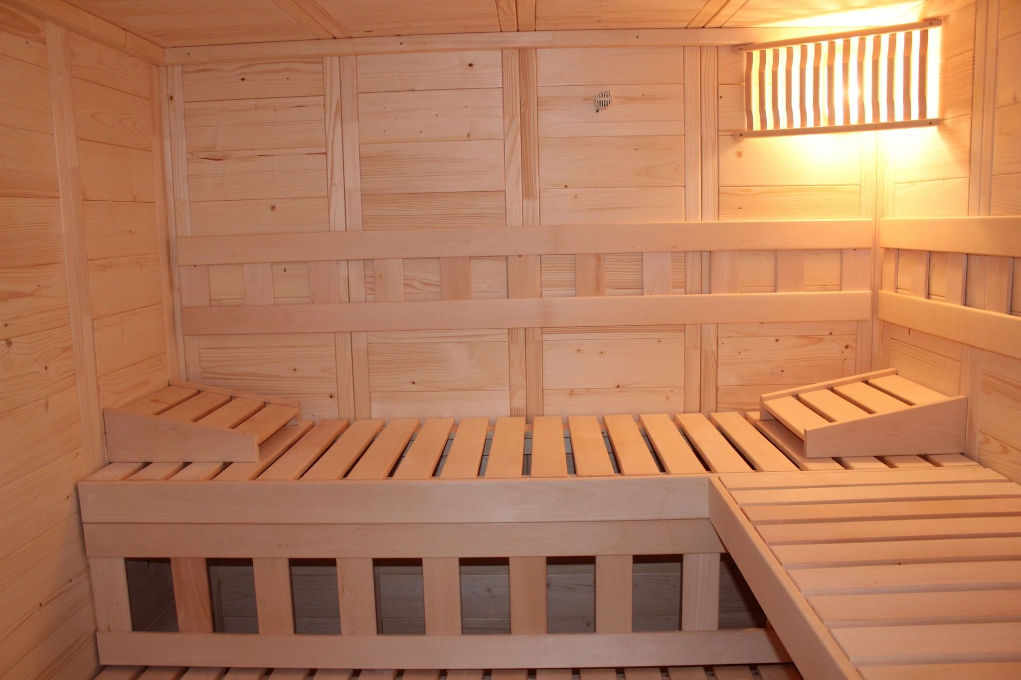 Finská sauna s dřevěnými lavicemi a teplým světlem