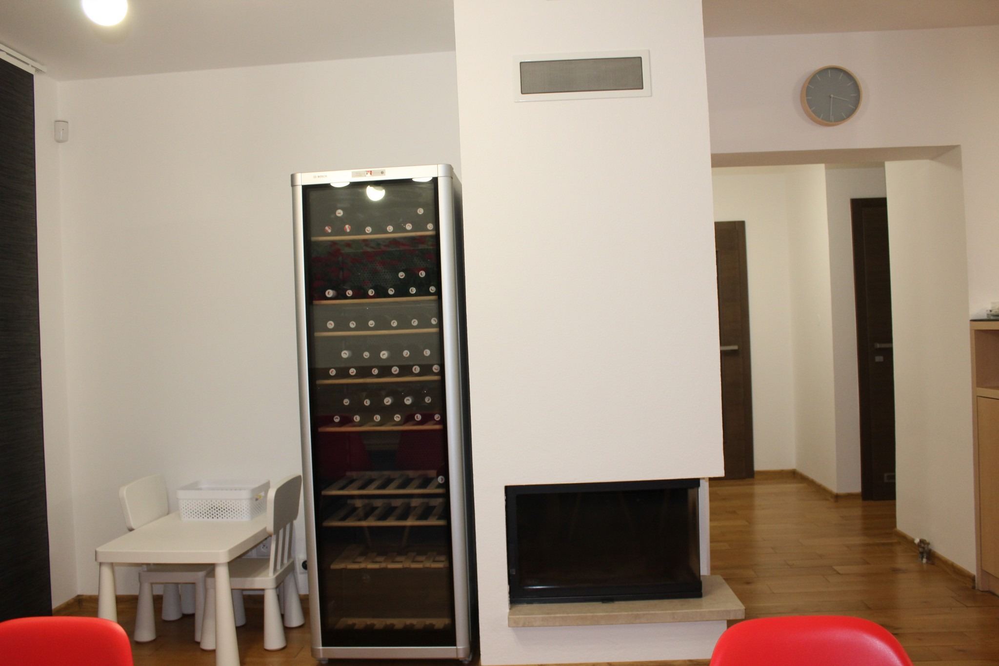 Vinotéka plná lahví a krb vedle jídelny